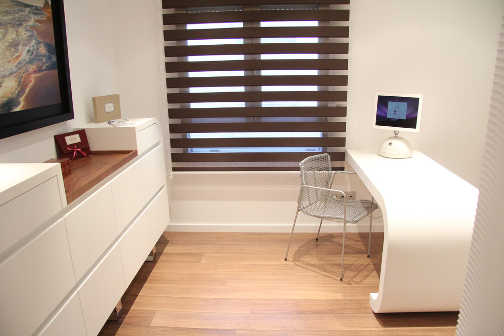 Kleines Modernes Arbeitszimmer ohne Kamin mit Arbeitsplatz, weißer Wandfarbe, braunem Holzboden und Einbau-Schreibtisch in Alicante-Costa Blanca