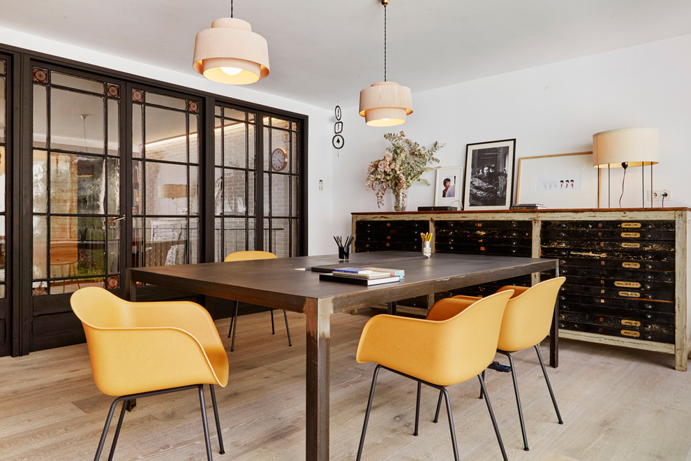 Industrial Arbeitszimmer ohne Kamin mit Studio, weißer Wandfarbe, hellem Holzboden und freistehendem Schreibtisch in Barcelona