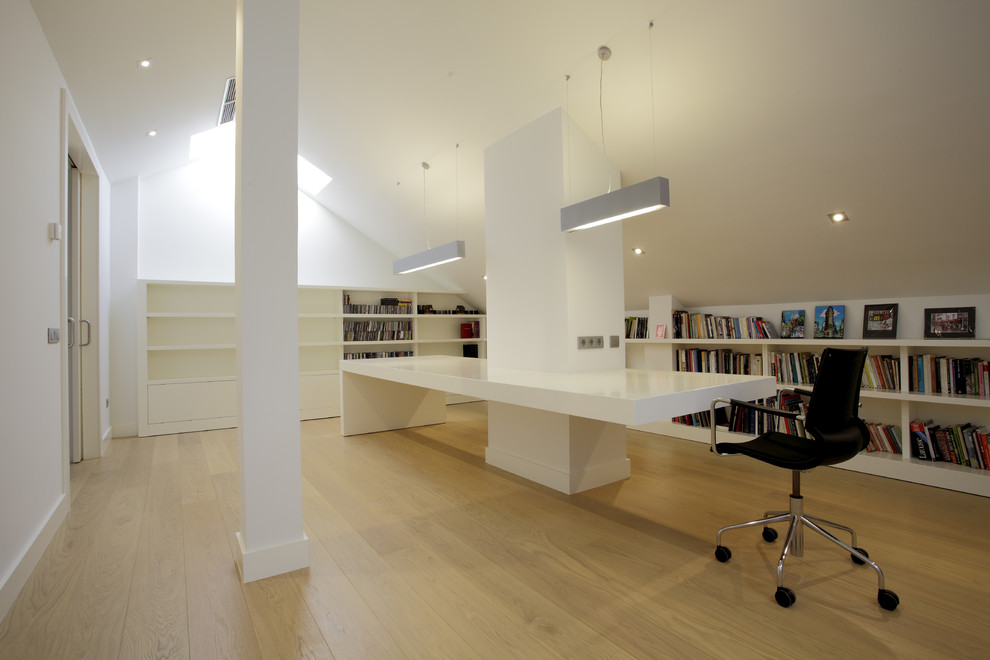 Großes Modernes Arbeitszimmer ohne Kamin mit Arbeitsplatz, weißer Wandfarbe, hellem Holzboden und Einbau-Schreibtisch in Madrid