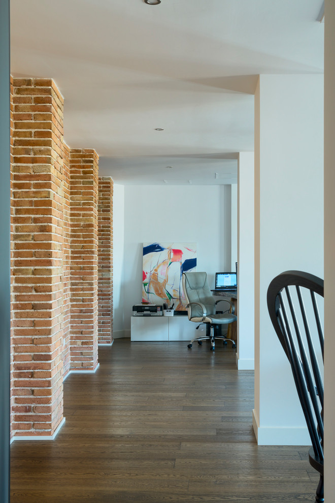 Imagen de despacho actual de tamaño medio con suelo marrón, paredes blancas y suelo de madera en tonos medios