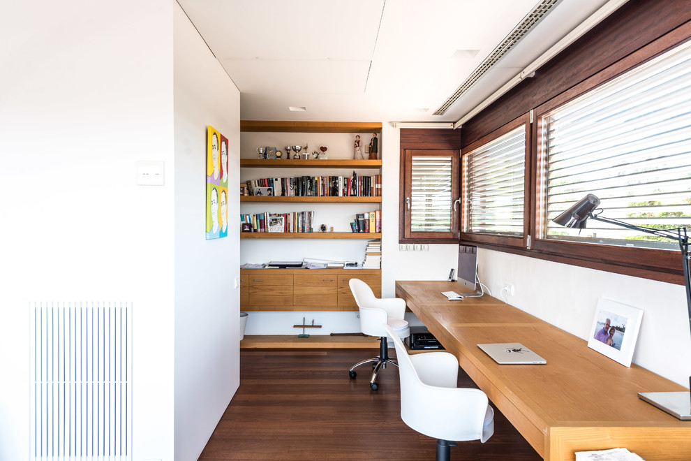 Mittelgroßes Klassisches Arbeitszimmer ohne Kamin mit Arbeitsplatz, weißer Wandfarbe, dunklem Holzboden und Einbau-Schreibtisch in Barcelona