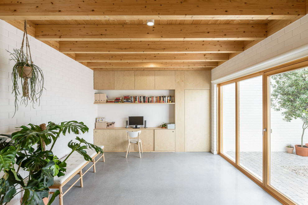 Aménagement d'un grand bureau contemporain avec un mur blanc, un bureau intégré, un sol gris, un plafond en bois, un mur en parement de brique et sol en béton ciré.