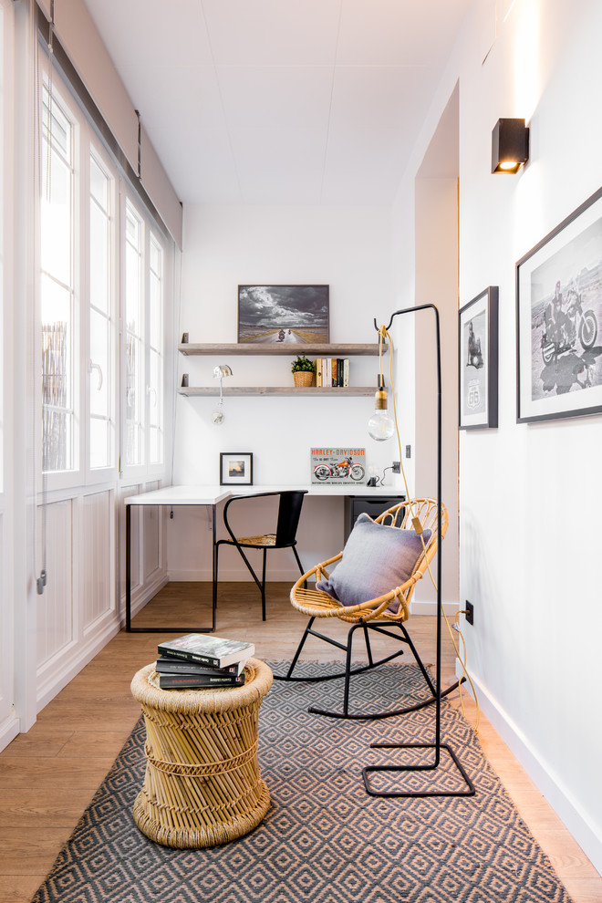 Photo of a contemporary study in Barcelona with white walls, medium hardwood flooring, a freestanding desk and beige floors.