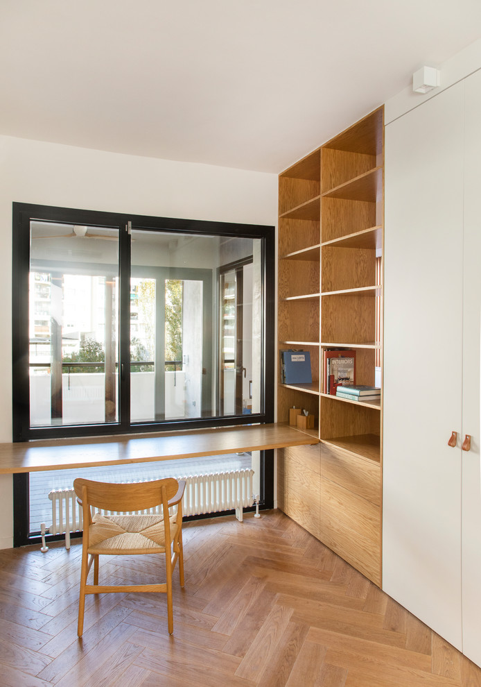 Réalisation d'un bureau design avec un mur blanc, un sol en bois brun, aucune cheminée, un bureau intégré et un sol marron.