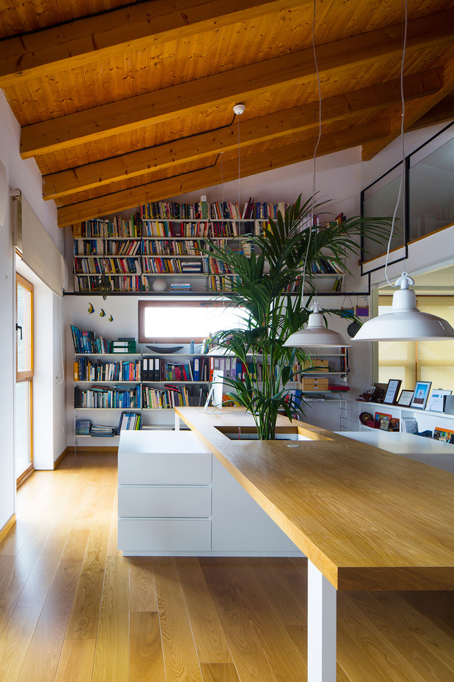 На фото: домашняя библиотека в современном стиле с белыми стенами и отдельно стоящим рабочим столом