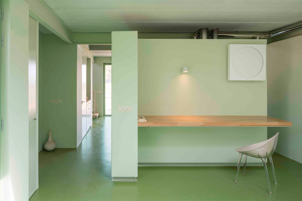 Идея дизайна: кабинет в современном стиле с зелеными стенами, бетонным полом, встроенным рабочим столом и зеленым полом