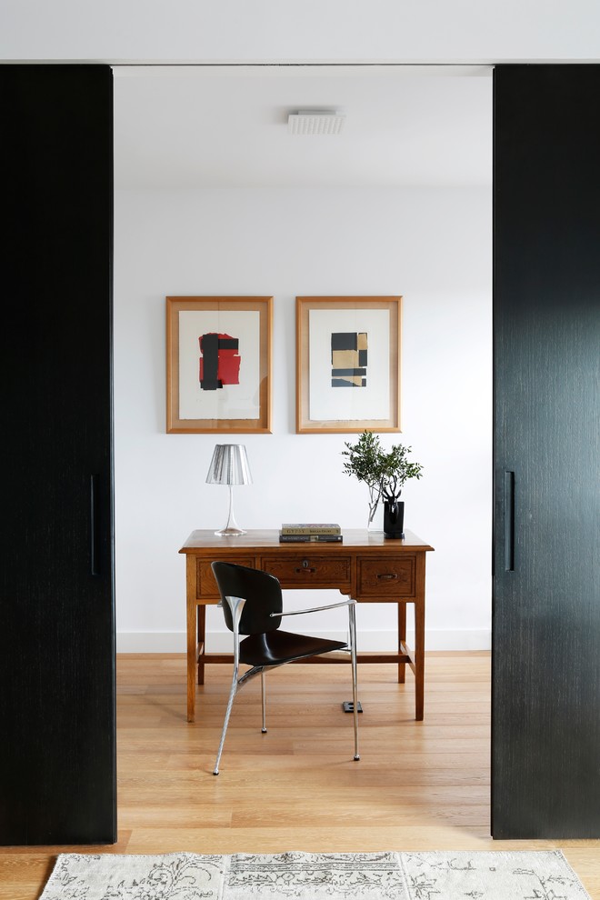 Kleines Modernes Arbeitszimmer ohne Kamin mit weißer Wandfarbe, freistehendem Schreibtisch und hellem Holzboden in Madrid