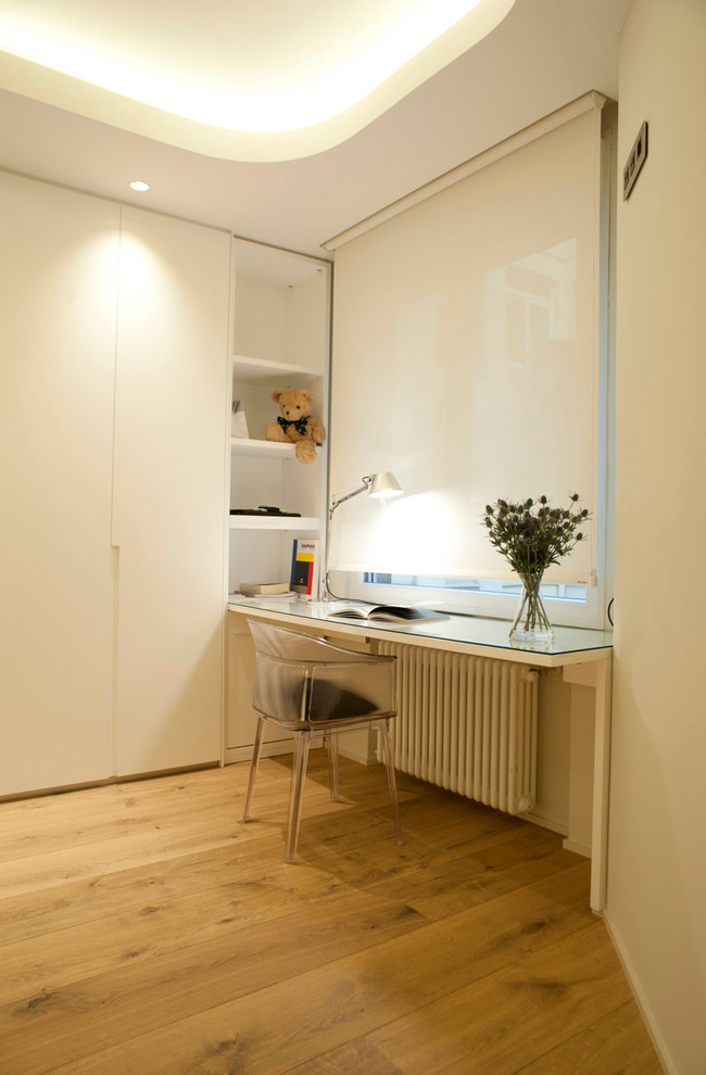 Foto de despacho actual pequeño sin chimenea con paredes blancas, suelo de madera en tonos medios y escritorio empotrado