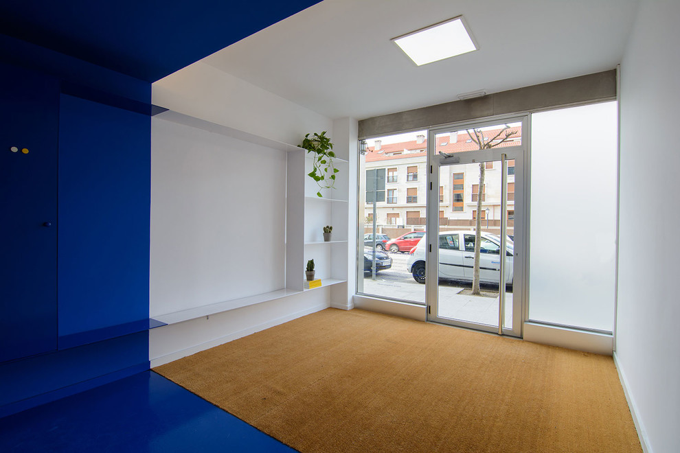 Imagen de estudio minimalista pequeño con paredes azules, escritorio empotrado y suelo marrón