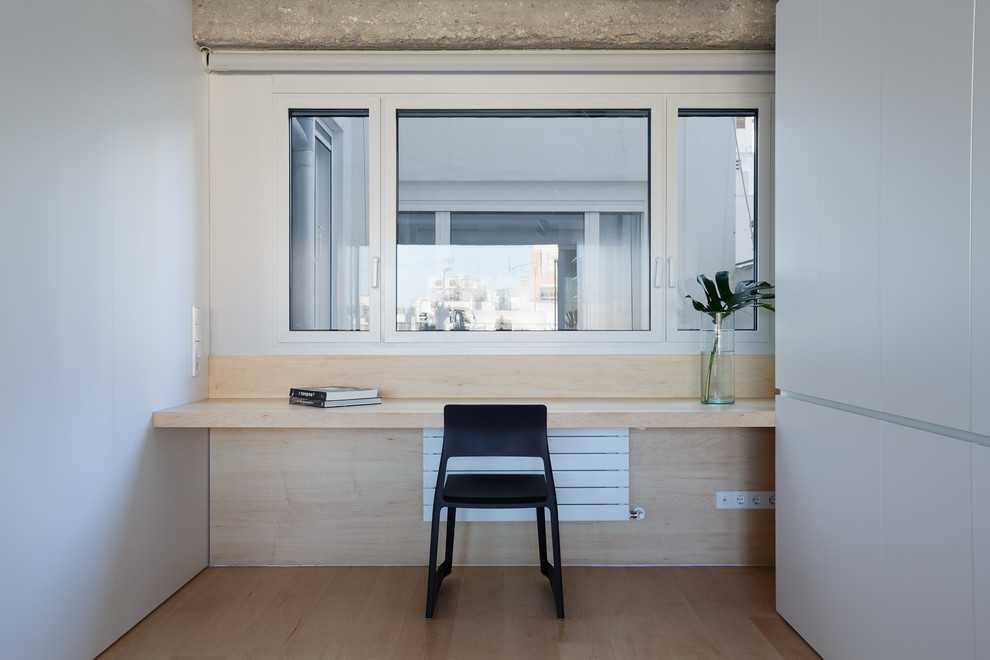 Diseño de estudio moderno con paredes blancas, suelo de madera clara y escritorio empotrado
