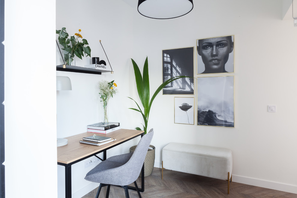 Skandinavisk inredning av ett mellanstort hemmastudio, med vita väggar, laminatgolv, ett fristående skrivbord och brunt golv