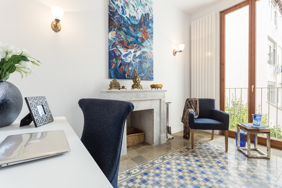 Mittelgroßes Stilmix Arbeitszimmer mit weißer Wandfarbe, Kamin, Arbeitsplatz, Keramikboden, verputzter Kaminumrandung und freistehendem Schreibtisch in Palma de Mallorca