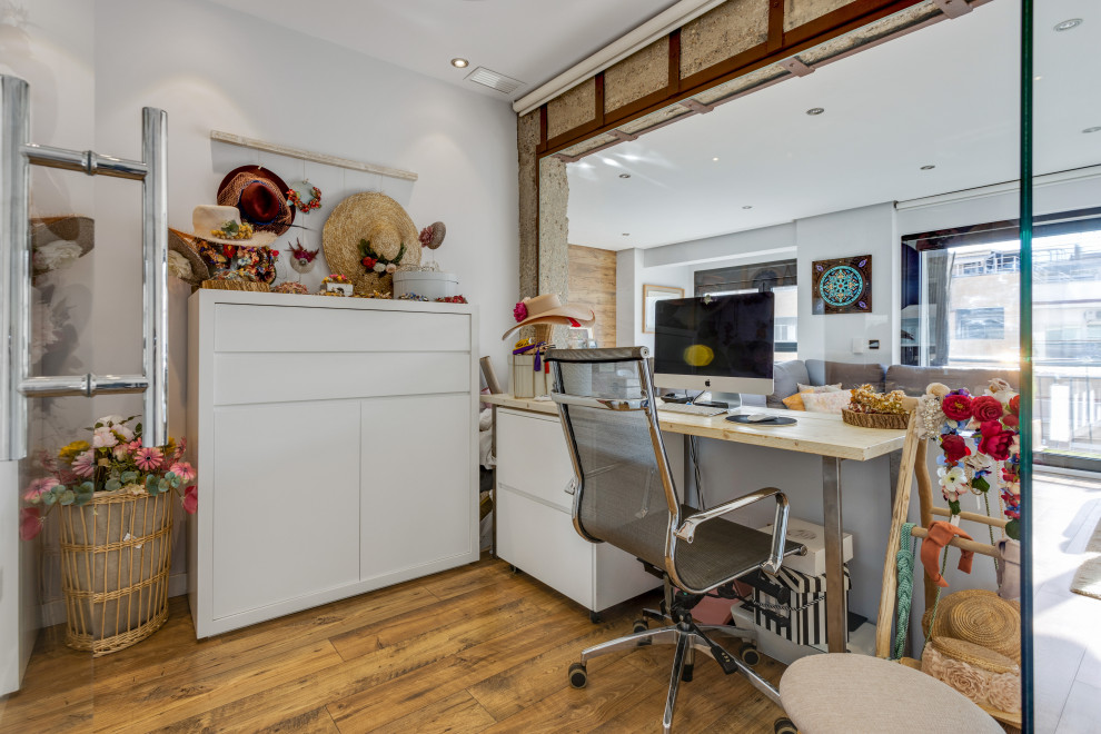 Eklektisk inredning av ett arbetsrum, med vita väggar, mellanmörkt trägolv, ett fristående skrivbord och brunt golv