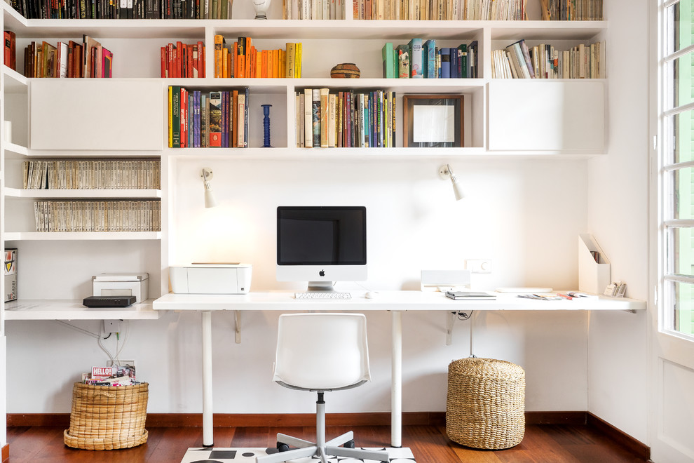 Cette photo montre un bureau tendance avec une bibliothèque ou un coin lecture, un mur blanc, parquet foncé, aucune cheminée, un bureau intégré et un sol marron.