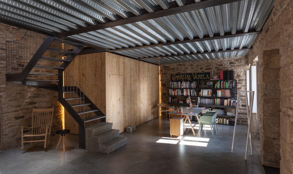 Exempel på ett mellanstort industriellt hemmabibliotek, med beige väggar, betonggolv och ett fristående skrivbord