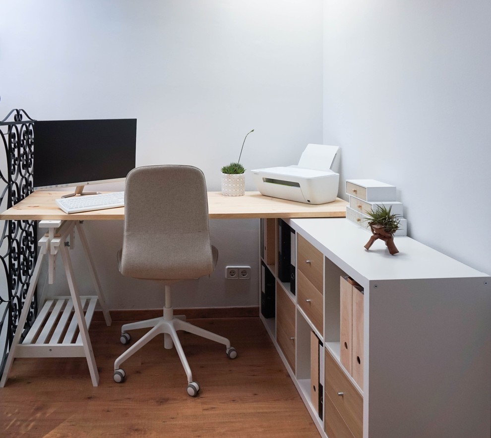 Immagine di un piccolo atelier nordico con pareti bianche, pavimento in laminato, scrivania autoportante e pavimento beige