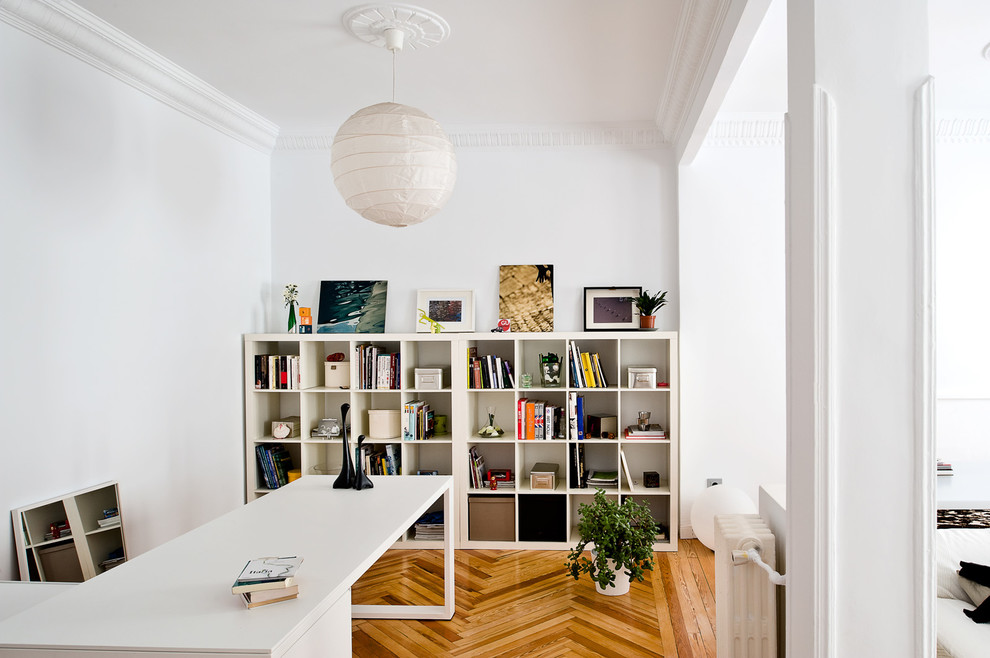 Mittelgroßes Nordisches Arbeitszimmer ohne Kamin mit Arbeitsplatz, weißer Wandfarbe, hellem Holzboden und freistehendem Schreibtisch in Madrid