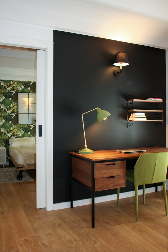 Kleines Modernes Arbeitszimmer ohne Kamin mit schwarzer Wandfarbe, braunem Holzboden, freistehendem Schreibtisch und braunem Boden in Barcelona