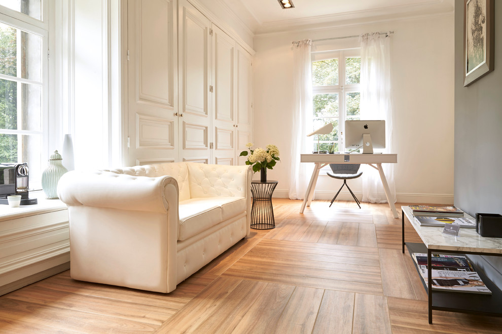 Mittelgroßes Klassisches Arbeitszimmer ohne Kamin mit Arbeitsplatz, weißer Wandfarbe, braunem Holzboden und freistehendem Schreibtisch in Madrid