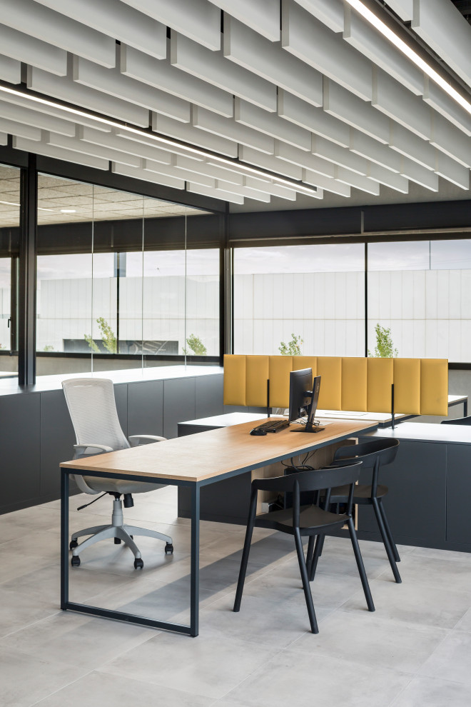 На фото: рабочее место в стиле лофт с серыми стенами, полом из керамогранита, отдельно стоящим рабочим столом и серым полом