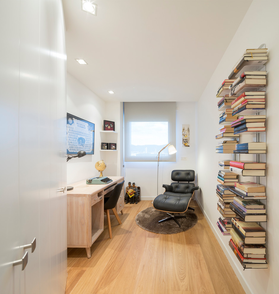 Modelo de despacho contemporáneo de tamaño medio sin chimenea con paredes blancas, suelo de madera en tonos medios y escritorio empotrado