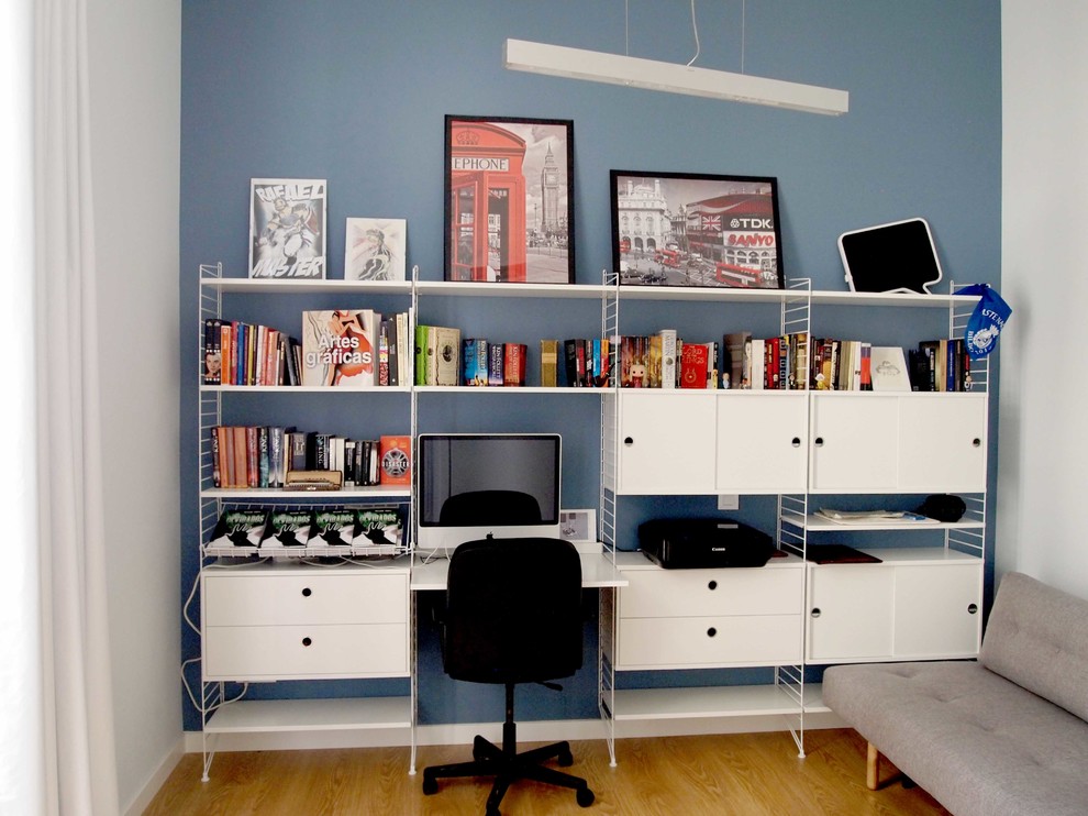 Foto de estudio contemporáneo pequeño sin chimenea con paredes azules, escritorio empotrado, suelo laminado y suelo marrón