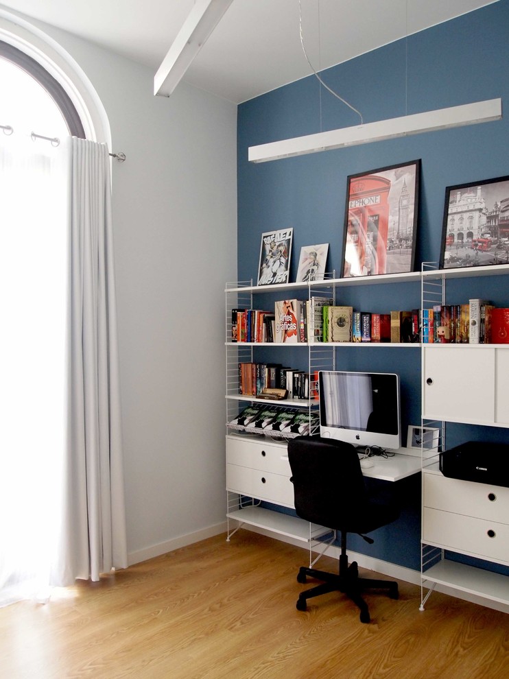 Idées déco pour un petit bureau contemporain de type studio avec un mur bleu, aucune cheminée, un bureau intégré, sol en stratifié et un sol marron.