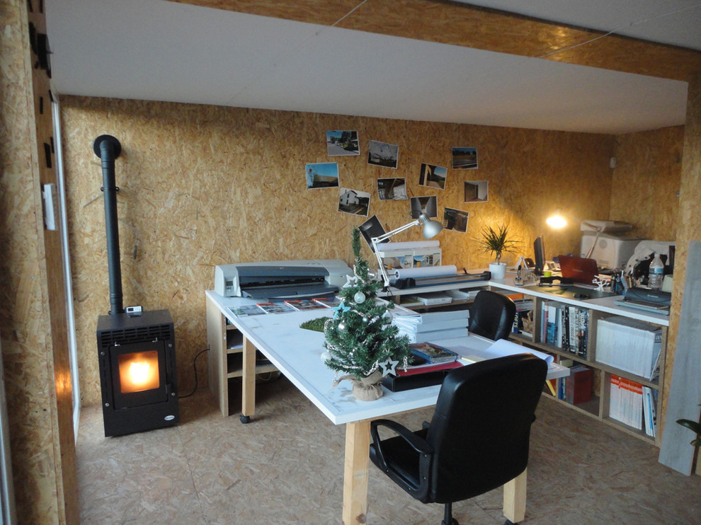 Imagen de estudio actual de tamaño medio con paredes beige, suelo de corcho, estufa de leña y escritorio empotrado