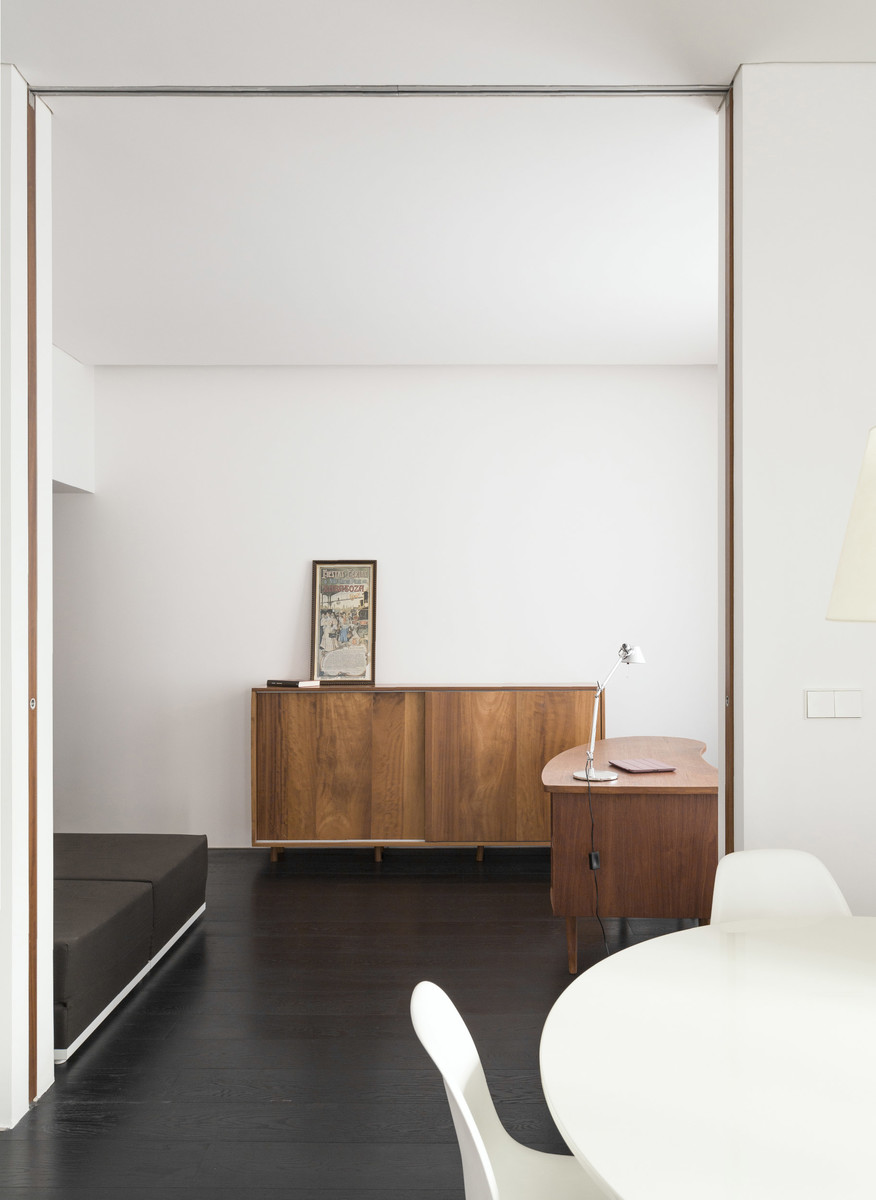 Imagen de estudio actual de tamaño medio con paredes blancas, suelo de madera oscura y escritorio independiente