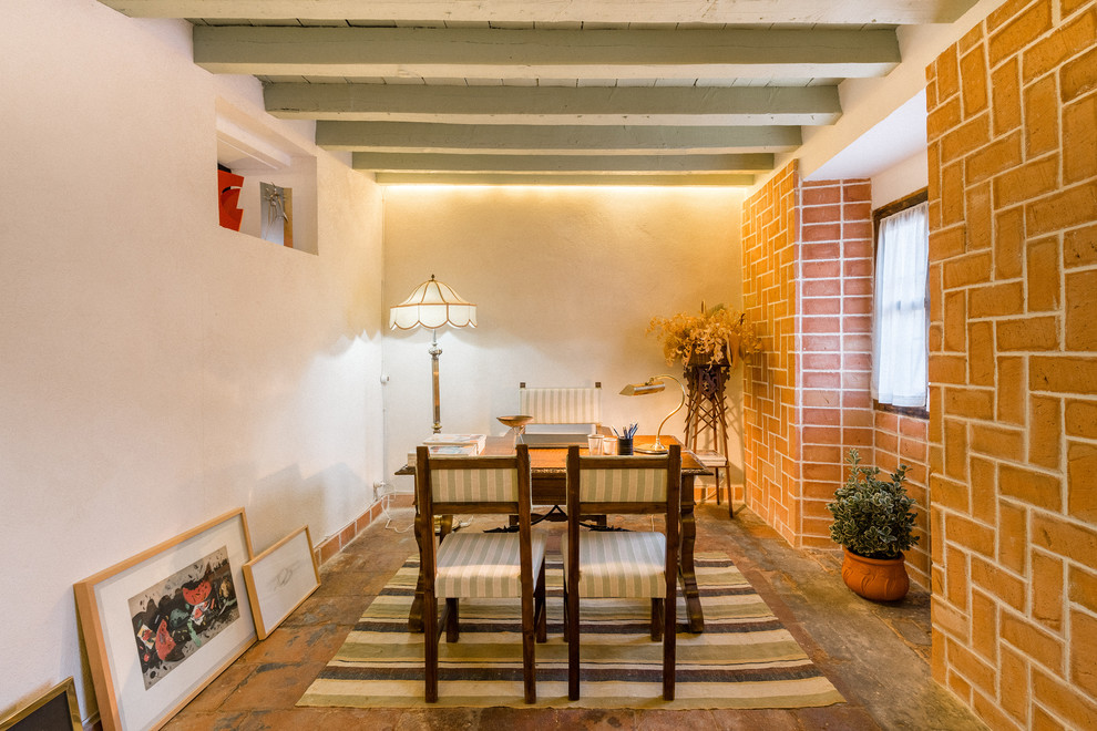 Mediterranes Arbeitszimmer mit Arbeitsplatz, weißer Wandfarbe, freistehendem Schreibtisch, orangem Boden und Terrakottaboden in Madrid