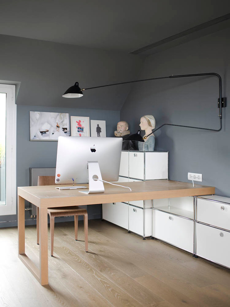 Modelo de despacho nórdico pequeño sin chimenea con paredes grises, suelo de madera clara y escritorio empotrado