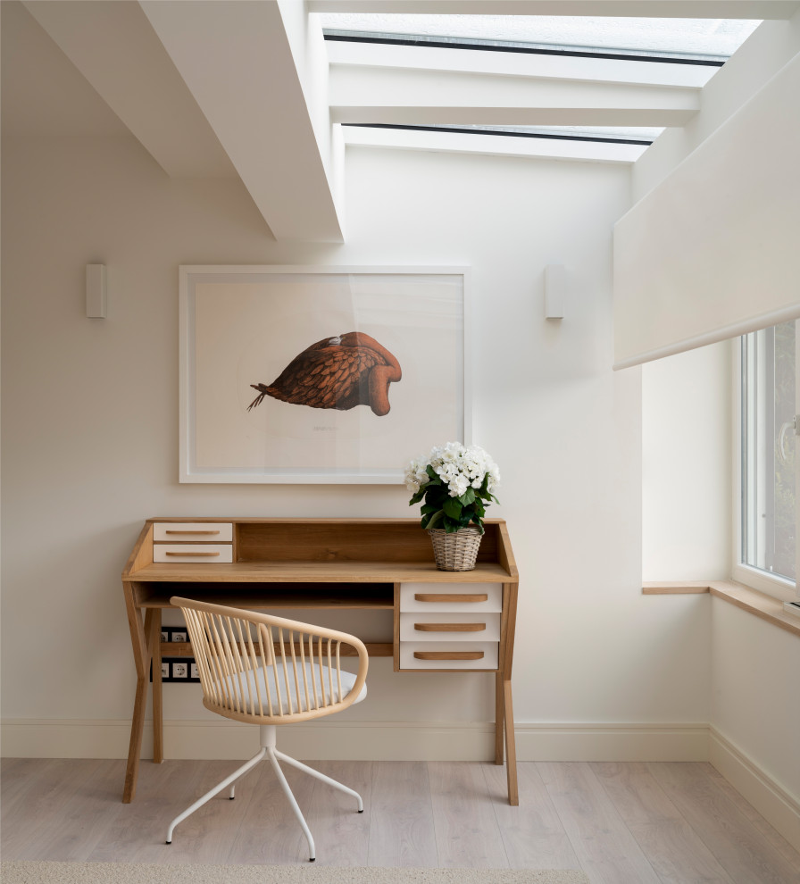 Пример оригинального дизайна: домашняя мастерская среднего размера в скандинавском стиле с белыми стенами, полом из ламината, отдельно стоящим рабочим столом и коричневым полом без камина