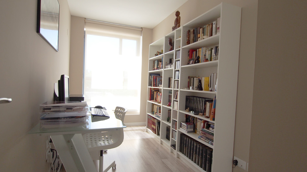 Ispirazione per uno studio minimal di medie dimensioni con libreria, pareti beige, parquet chiaro, scrivania autoportante e pavimento beige