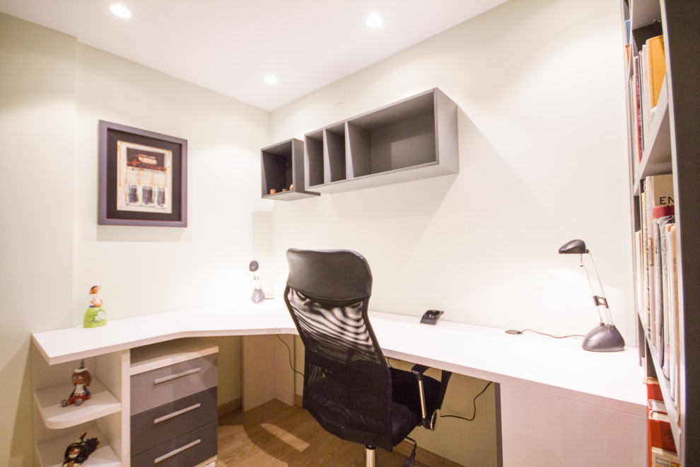 Modelo de despacho contemporáneo pequeño sin chimenea con paredes beige, suelo laminado y escritorio empotrado