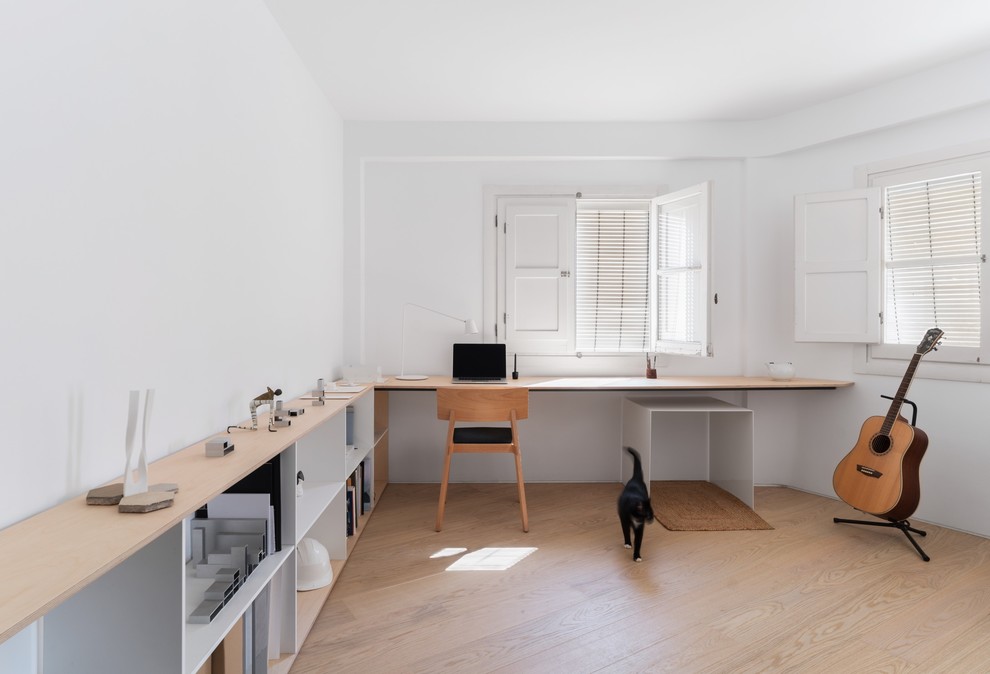 Idées déco pour un grand bureau scandinave avec un mur blanc, un sol en bois brun, un bureau intégré et un sol marron.