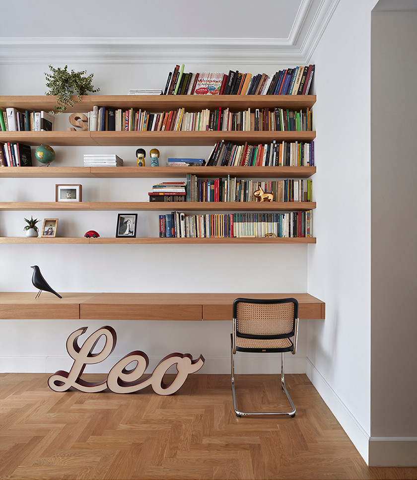 Ejemplo de despacho retro con biblioteca, paredes blancas, suelo de madera clara y escritorio empotrado