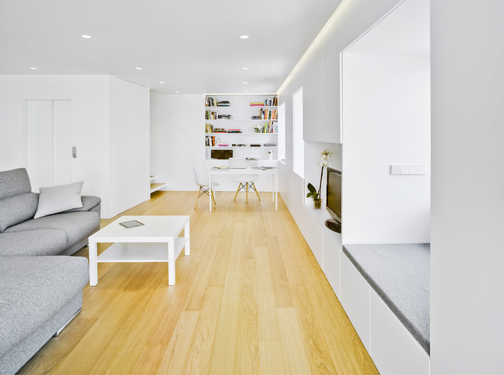 Modelo de estudio contemporáneo de tamaño medio con paredes blancas, suelo de madera clara y escritorio independiente