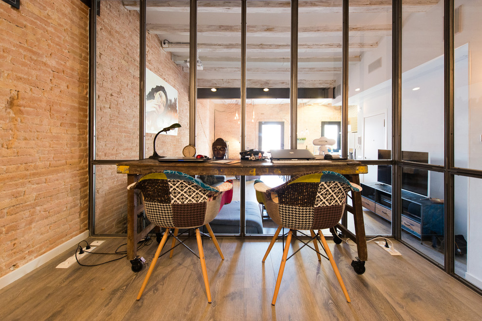 Kleines Industrial Arbeitszimmer ohne Kamin mit Arbeitsplatz, oranger Wandfarbe, braunem Holzboden und freistehendem Schreibtisch in Barcelona