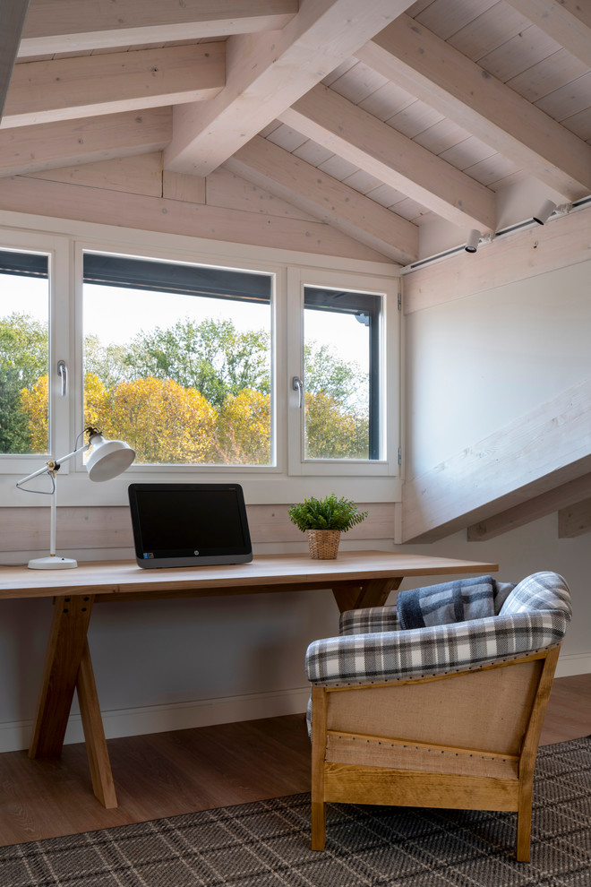 Foto de estudio tradicional renovado grande sin chimenea con paredes blancas, suelo laminado, escritorio independiente y suelo marrón