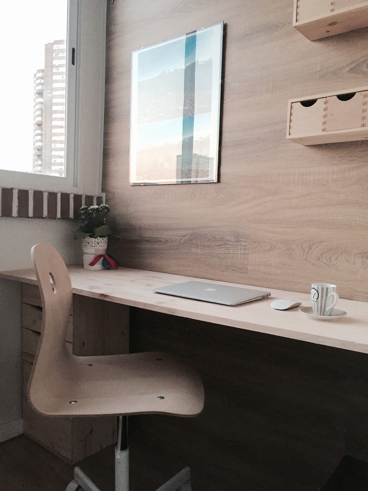 Medium sized scandi study in Madrid with white walls, medium hardwood flooring, no fireplace and a built-in desk.
