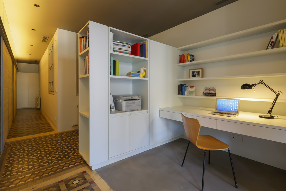 Modern inredning av ett litet hemmabibliotek, med vita väggar och ett inbyggt skrivbord
