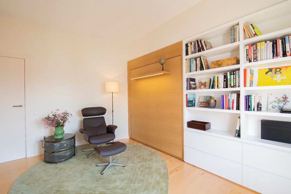 Exemple d'un bureau tendance de taille moyenne avec une bibliothèque ou un coin lecture, un mur blanc, parquet clair et un bureau indépendant.