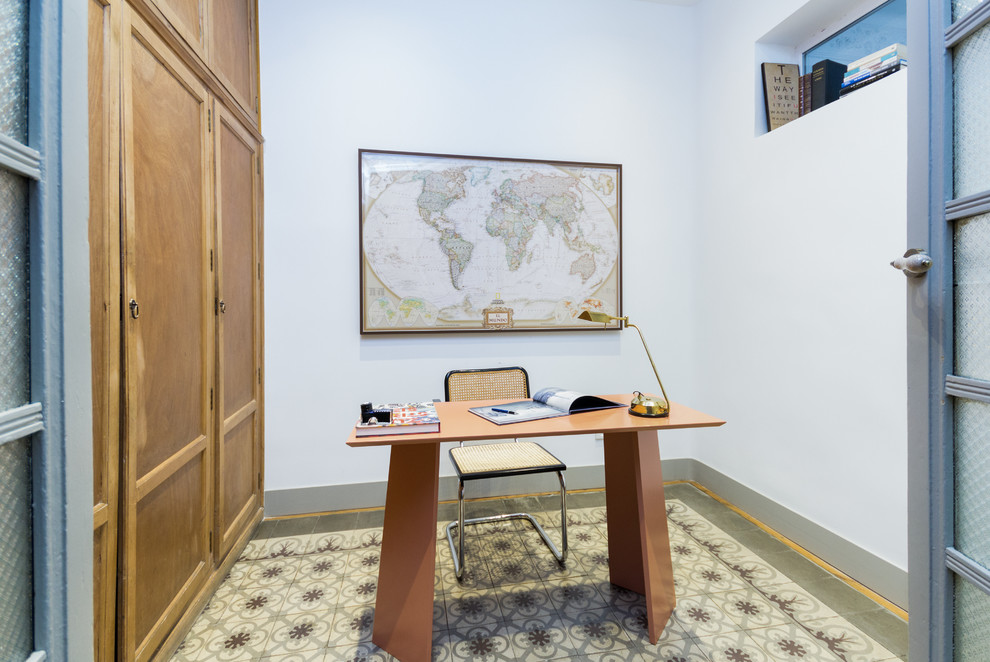 Modelo de despacho mediterráneo con escritorio independiente, paredes blancas, suelo de baldosas de cerámica y suelo multicolor
