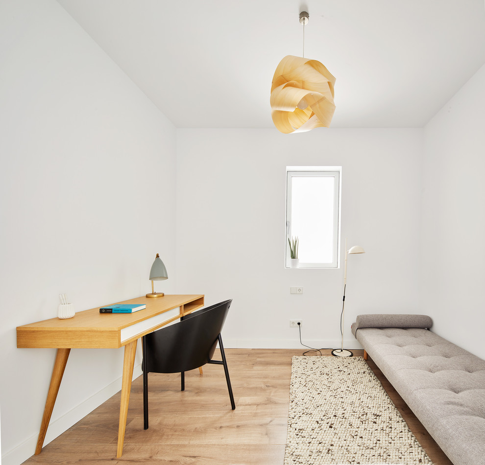 Modern inredning av ett hemmastudio, med vita väggar, mellanmörkt trägolv och ett fristående skrivbord