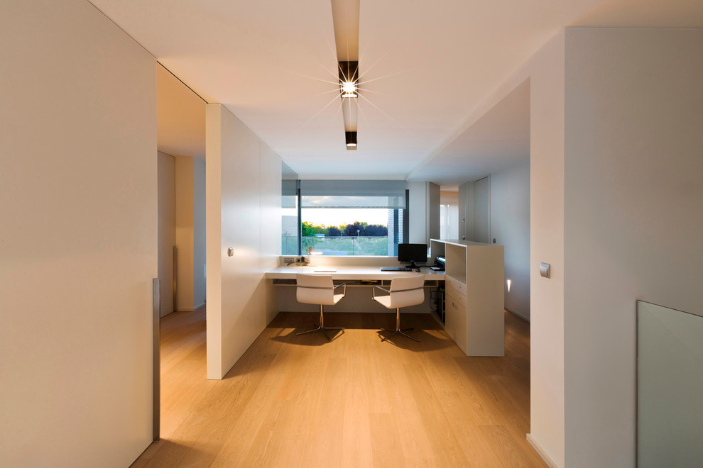 Foto de despacho contemporáneo de tamaño medio con paredes blancas, suelo de madera en tonos medios y escritorio empotrado