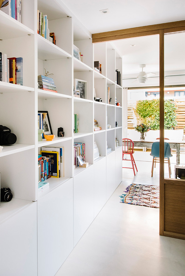 Idée de décoration pour un bureau minimaliste avec une bibliothèque ou un coin lecture, un mur blanc, sol en béton ciré, un bureau intégré et un sol gris.