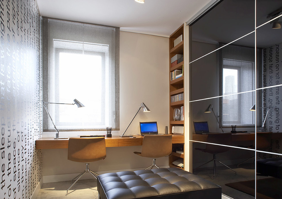 Modern inredning av ett mellanstort hemmastudio, med vita väggar, betonggolv, ett inbyggt skrivbord och grått golv