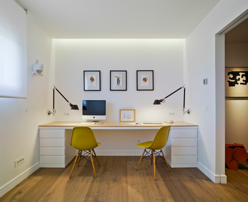 Modelo de despacho contemporáneo de tamaño medio sin chimenea con paredes blancas, suelo de madera en tonos medios, escritorio empotrado y suelo marrón