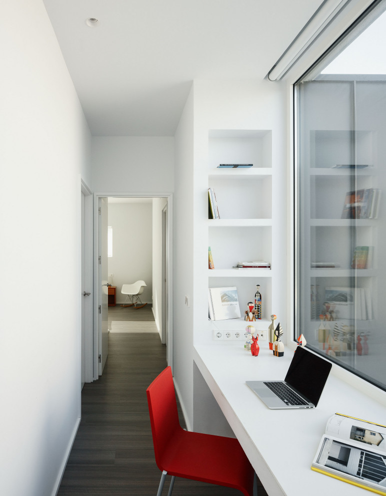 Modernes Arbeitszimmer mit weißer Wandfarbe, dunklem Holzboden, Einbau-Schreibtisch und grauem Boden in Sonstige