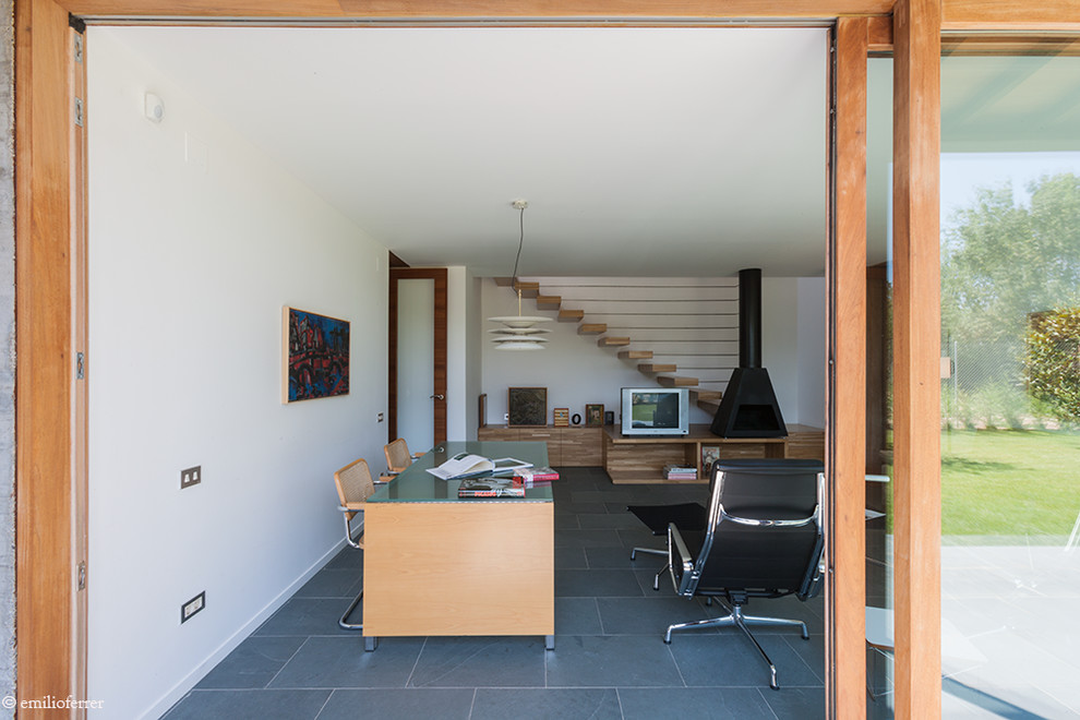 Modern inredning av ett stort hemmastudio, med vita väggar, en standard öppen spis och ett fristående skrivbord